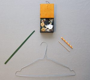 Matériel pour un sistre: un cintre en métal, du fil métallique, un bâtonnet en bois, des boutons